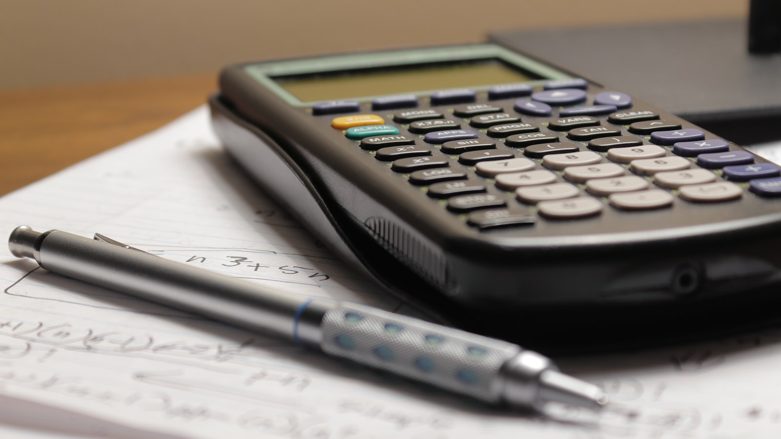 Calculator și pix așezate pe o foaie cu calcule