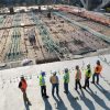 Echipă de muncitori cu căști de protecție și veste reflectorizante, pe platforma unui șantier